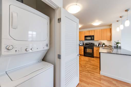 A white washing machine and dryer in a kitchen at The Grand Apartments, Oakland 94612